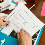 Hands examining a printed report with population and timeline chart during a business meeting.